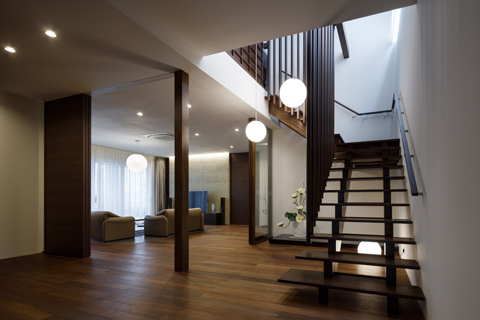 統一された照明でデザインされた玄関と階段とリビングルームの内観写真